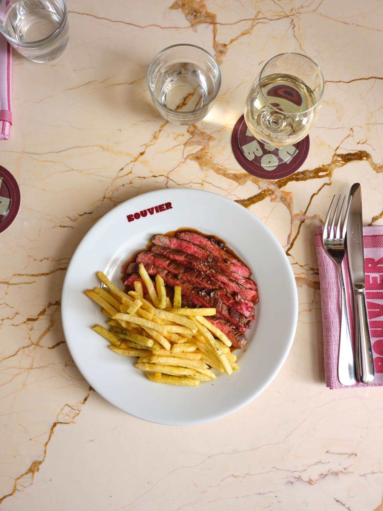 Steak and fries, served on a plate with a glass of wine